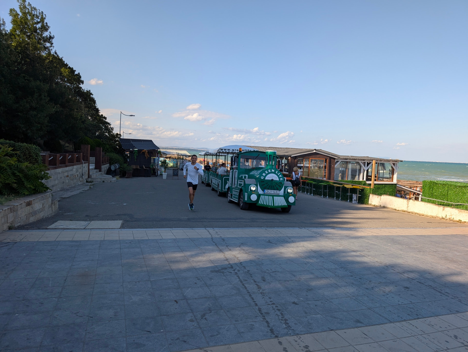Runner on the seaside promenade next to the little tourist train